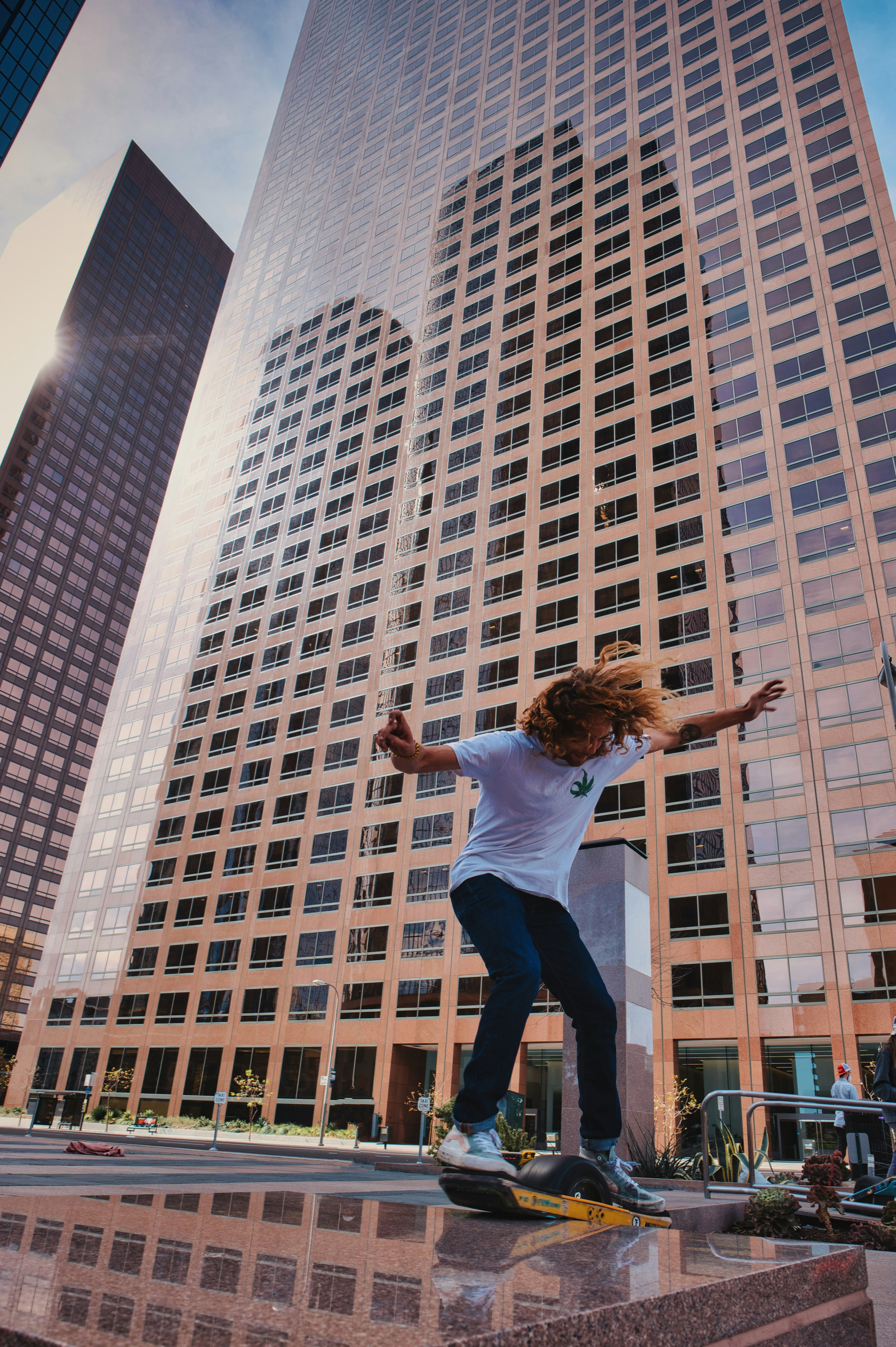 woman in white shirt and black pants jumping on mid air near white concrete building during